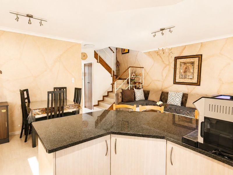 Open plan living and dining area featuring a kitchen with granite countertops and a staircase leading to the upper level.