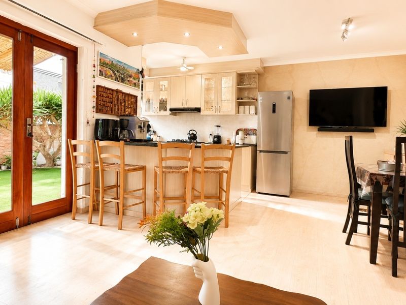 Open plan living and kitchen area featuring a breakfast bar, modern cabinetry, and double glass doors providing direct access to the rear garden.