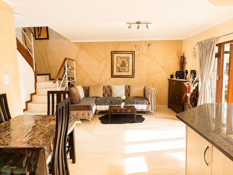 Open plan living and dining area featuring a staircase, granite kitchen countertops, and access to the outdoors through french doors.