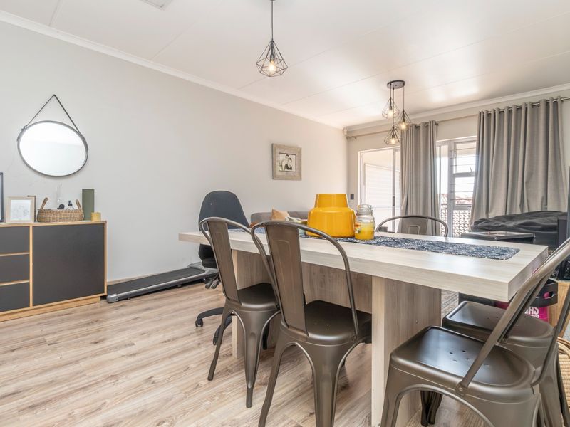 An open-plan living and dining area featuring modern laminate flooring, pendant lighting, and a sliding glass door leading to an outdoor space.