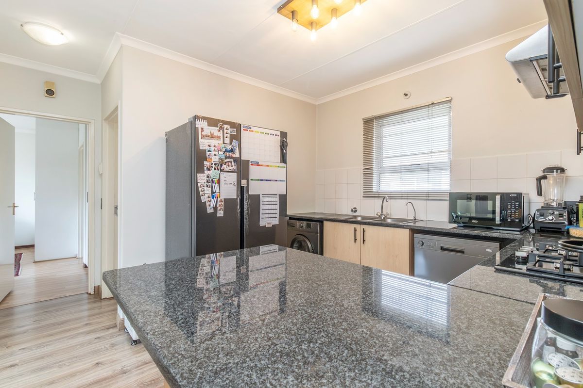 A functional kitchen featuring granite countertops, ample cabinetry, a built-in hob, and an extractor fan, with a tiled backsplash and neutral finishes.