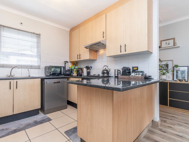 A functional kitchen featuring light wood cabinetry, granite countertops, a tiled backsplash, and integrated appliances, offering a clean and practical cooking space.