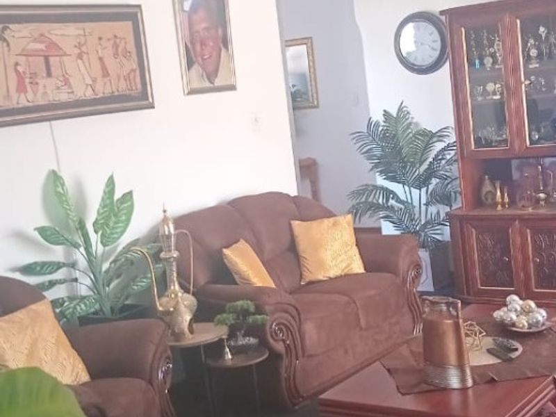 A living room area featuring neutral walls and carpeted flooring, providing a functional space for relaxation.