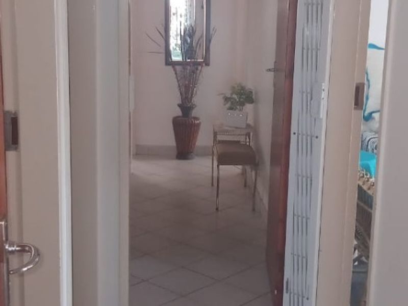 A functional hallway featuring neutral tiled flooring and a folding door, providing access to adjacent rooms within the home.
