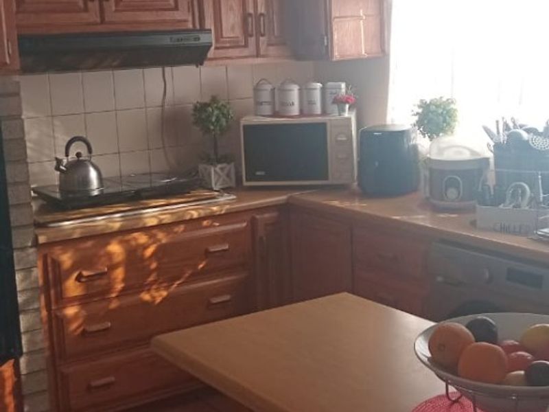 A functional kitchen featuring traditional wooden cabinetry, tiled flooring, and a tiled backsplash, offering a classic layout with ample storage space.