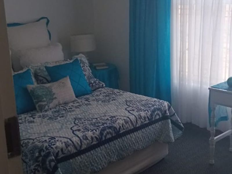 A standard bedroom featuring carpeted flooring and window treatments, providing a functional space for rest.