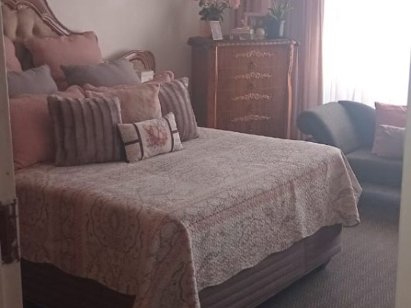 A carpeted bedroom featuring neutral walls and window treatments, offering a comfortable and functional sleeping space.