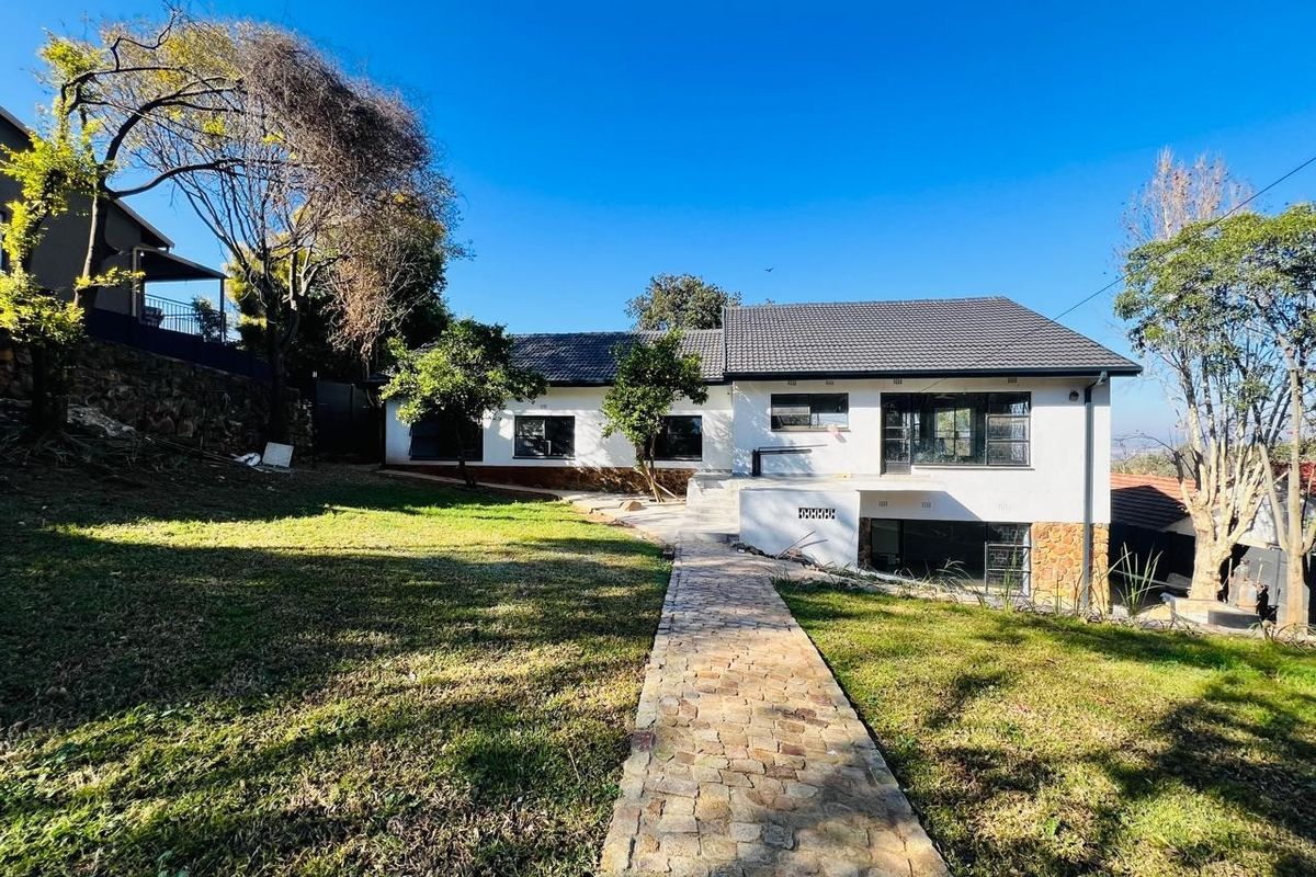 Rear view of the house featuring a stone paved walkway leading to the entrance, stone cladding accents, and a well-maintained garden area.