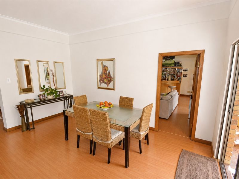 A bright dining room featuring laminate flooring, an archway leading to an adjacent room, and a sliding glass door providing access to the outdoors.
