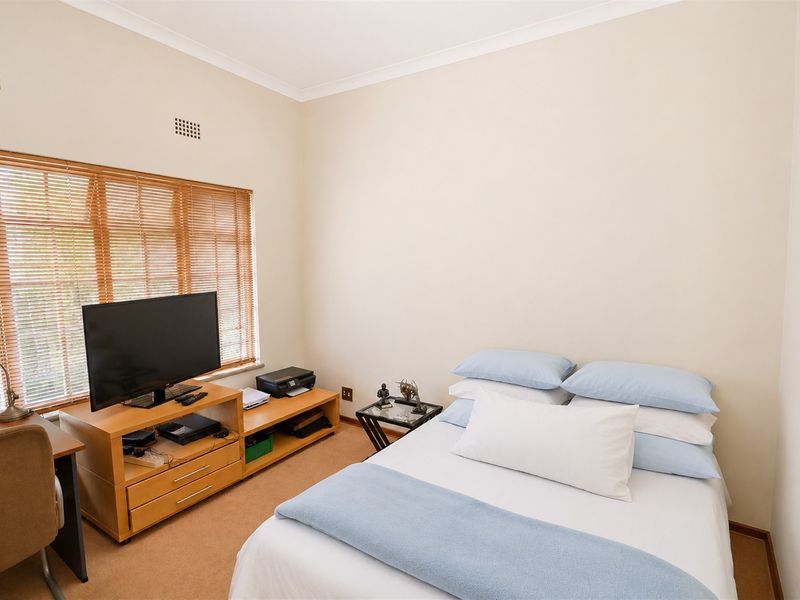 A functional bedroom featuring neutral walls, carpeted flooring, and window blinds, providing a comfortable and well-lit living space.