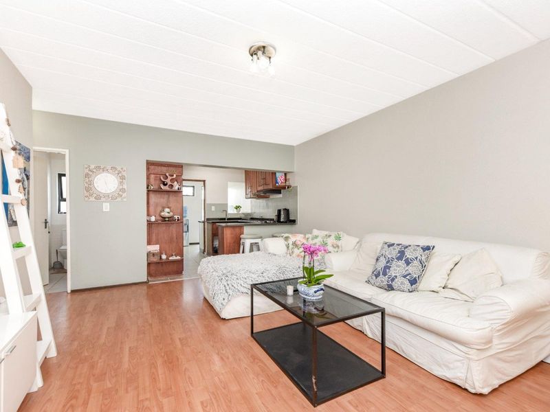 Open plan living area featuring laminate flooring and a connected kitchen space with built-in cabinetry and shelving.