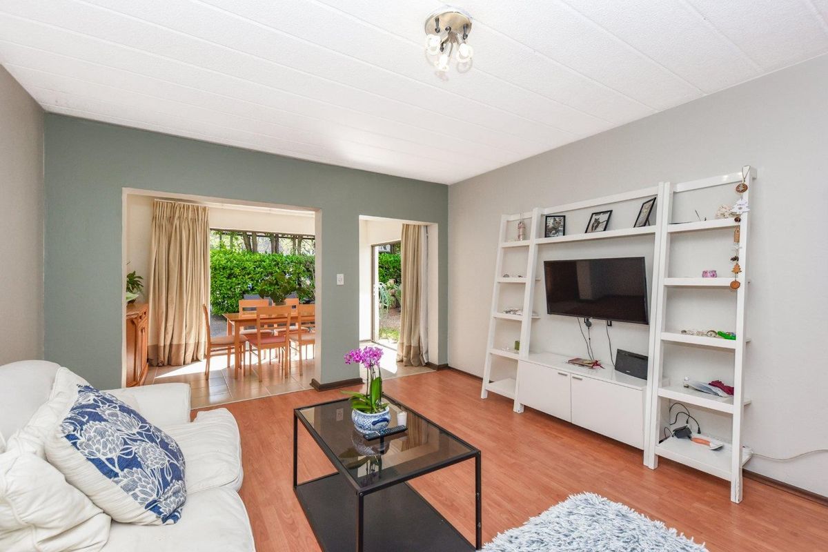 A bright living room featuring laminate flooring and direct access through sliding glass doors to an outdoor patio area.