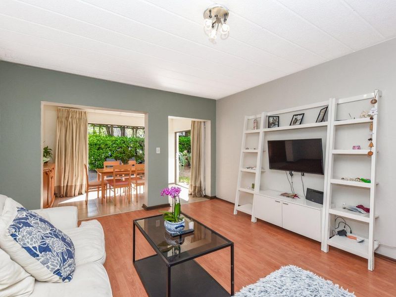 A bright living room featuring laminate flooring and direct access through sliding glass doors to an outdoor patio area.