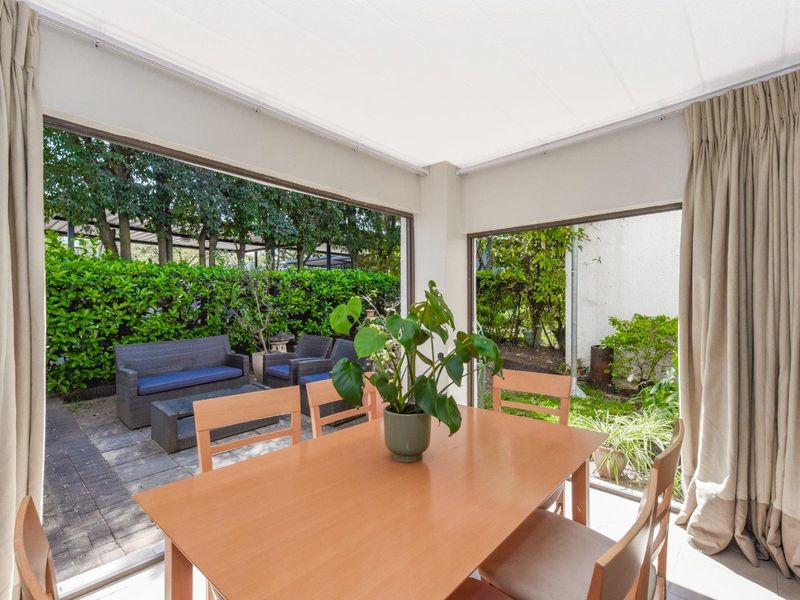 A bright, covered patio area featuring large sliding glass doors that provide seamless access to the outdoor garden space.