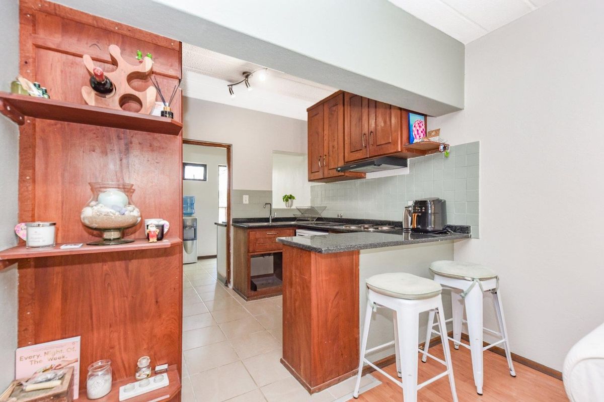 Compact kitchen featuring wooden cabinetry, granite countertops, and a tiled backsplash, with an open-plan layout connecting to the living area.