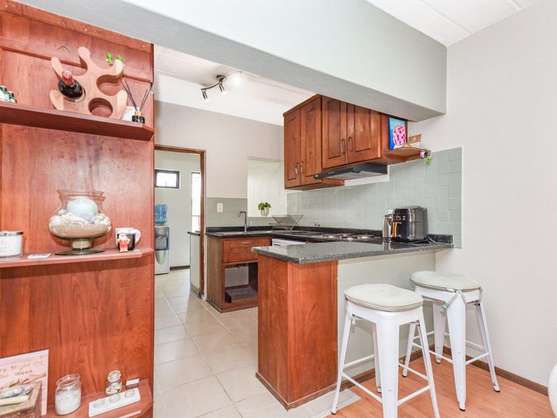 Compact kitchen featuring wooden cabinetry, granite countertops, and a tiled backsplash, with an open-plan layout connecting to the living area.