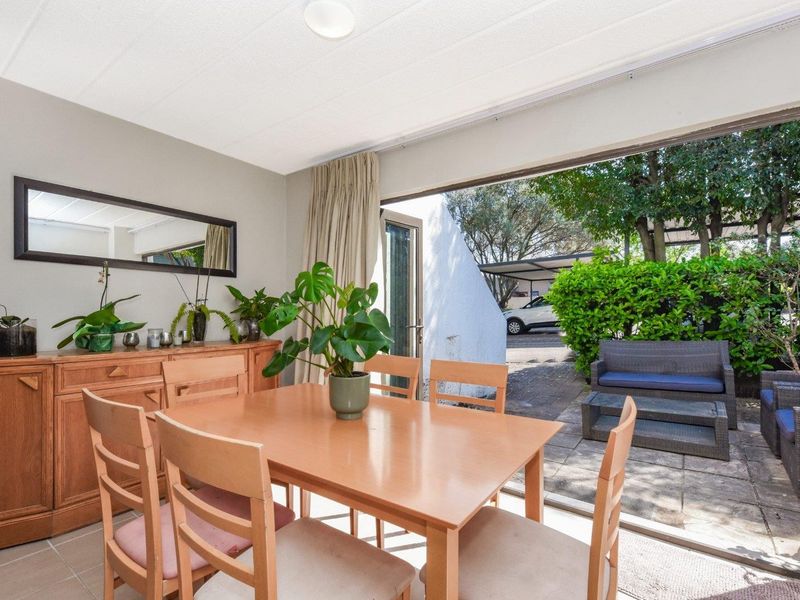 Dining area featuring tiled flooring and a large sliding glass door providing direct access to the outdoor patio and garden area.