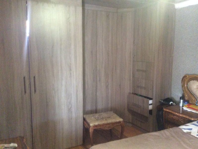Bedroom featuring light wood-grain built-in cupboards with integrated drawers and laminate flooring.