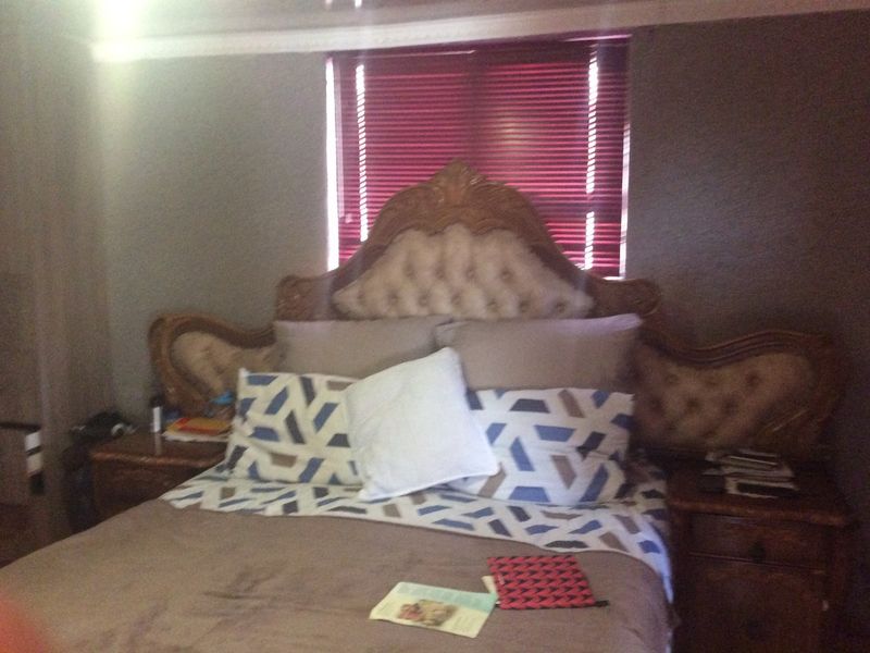 A bedroom featuring crown molding and venetian blinds over the window.