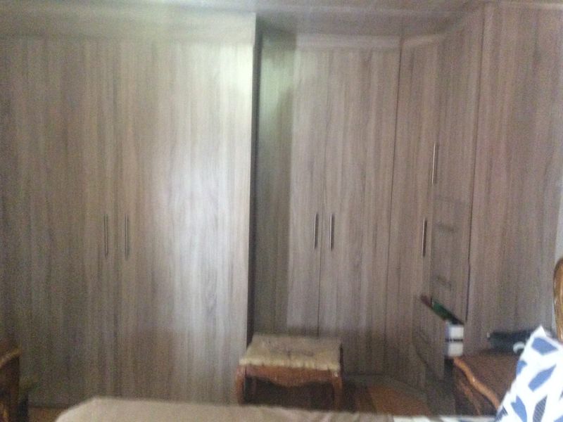 A bedroom featuring extensive light wood-grain built-in cupboards providing ample storage space.