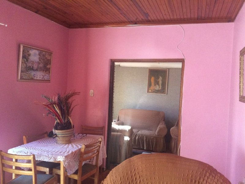 A living area featuring a timber ceiling and pink wall finishes, with an open doorway leading to an adjacent room.