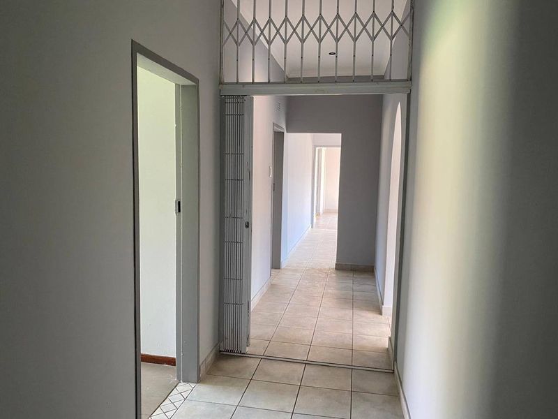 A bright, tiled hallway featuring a security gate and multiple doorways leading to various rooms within the home.
