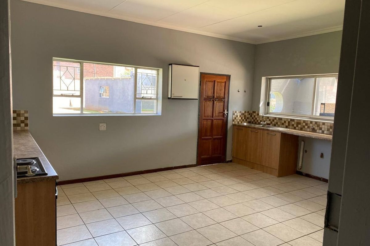 Spacious kitchen featuring built-in cabinetry, laminate countertops, a gas hob, and tiled flooring, offering a functional layout ready for modern updates.