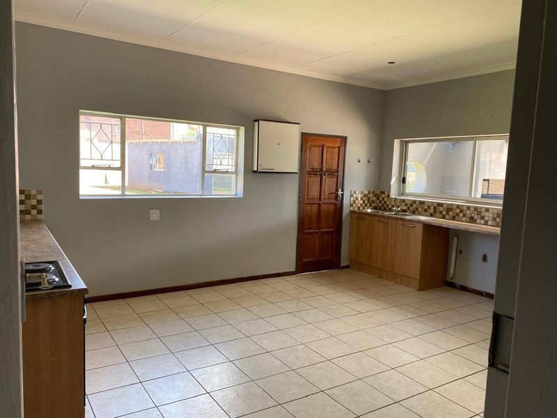 Spacious kitchen featuring built-in cabinetry, laminate countertops, a gas hob, and tiled flooring, offering a functional layout ready for modern updates.