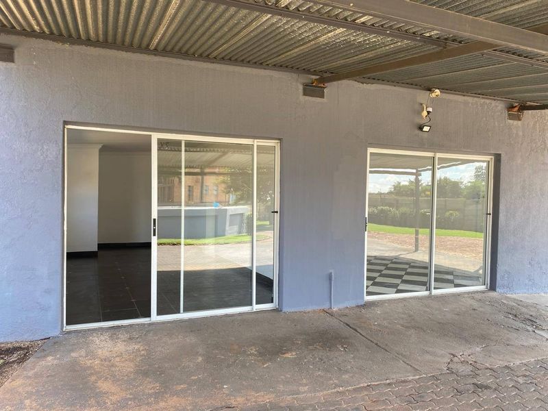 Covered patio area featuring concrete flooring and dual sliding glass doors providing access to the interior living space.
