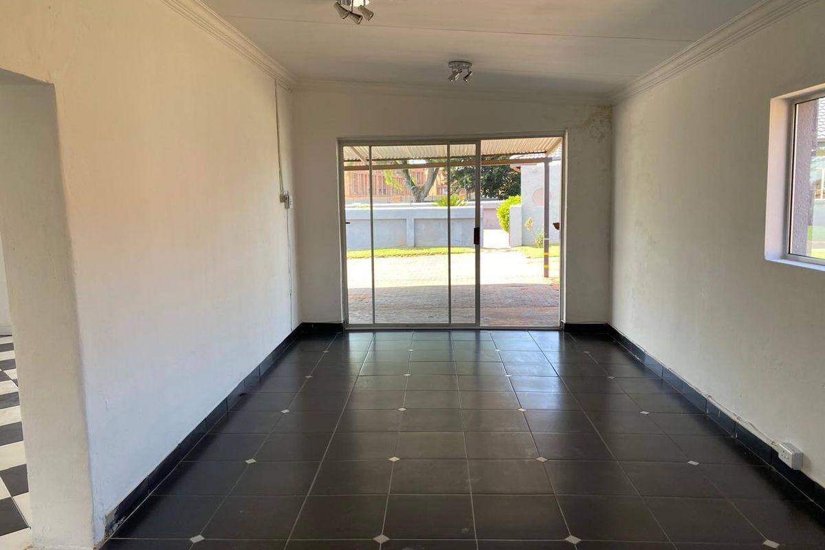An empty living room featuring dark ceramic floor tiles, coved ceilings, and a sliding glass door providing access to the exterior.