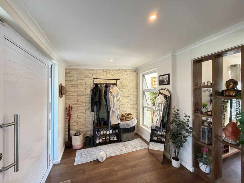 Welcoming entrance hall featuring a textured stone veneer feature wall, modern laminate flooring, and recessed downlighting.
