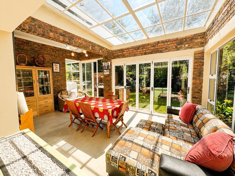 Spacious open-plan living and dining area featuring exposed brick walls, a large glass skylight, and bi-fold doors opening to the garden.