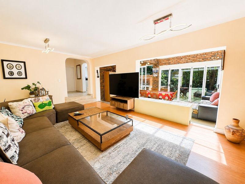 Spacious open-plan living area featuring laminate flooring, exposed brick accents, and large sliding glass doors providing seamless access to the outdoor patio.