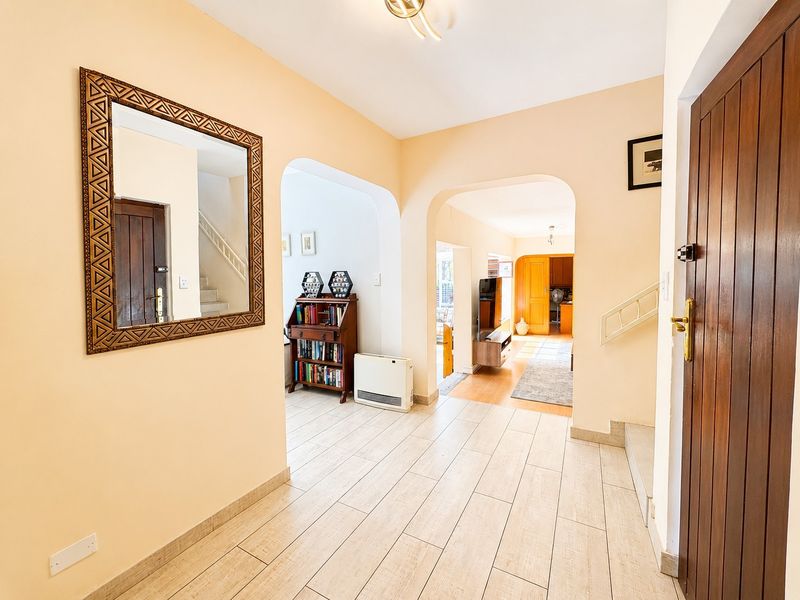 Welcoming entrance hall featuring light-toned tiled flooring, arched architectural transitions, and a solid timber front door leading into the main living areas.