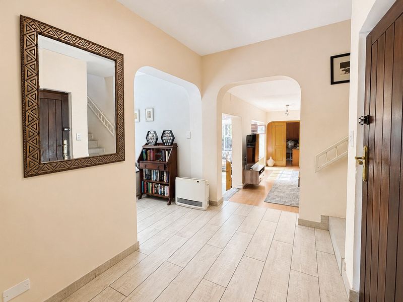 Welcoming entrance hall featuring tiled flooring, arched architectural details, and a staircase leading to the upper level of the townhouse.