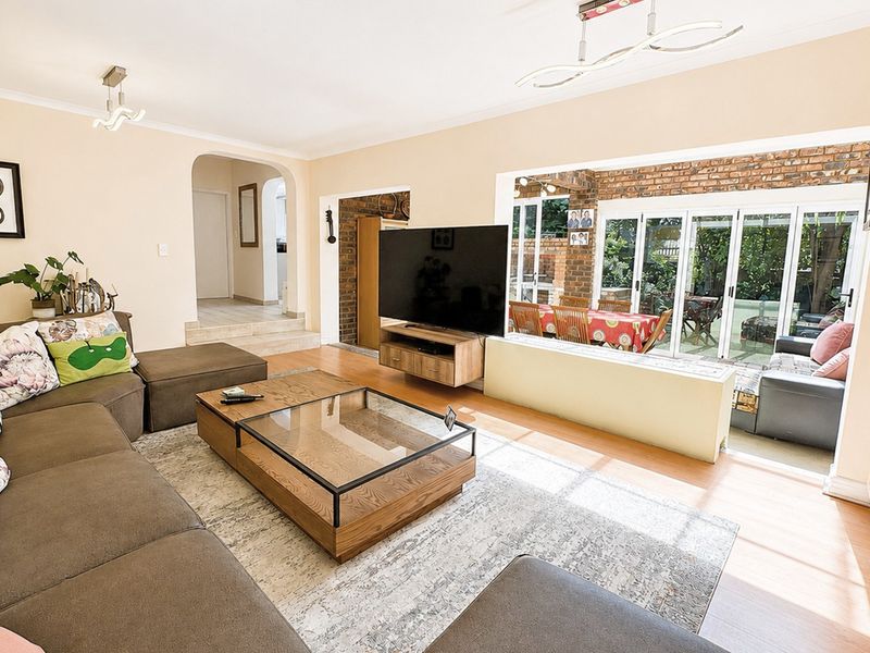 Spacious open-plan living area featuring laminate flooring, an arched entryway, and large sliding glass doors that provide seamless access to the outdoor patio.