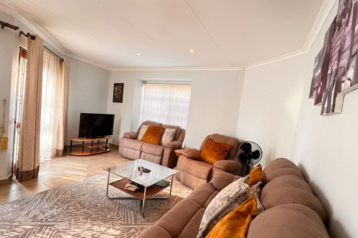 A comfortable living room featuring tiled flooring, recessed downlighting, and coved ceiling details, providing a functional and inviting space for relaxation.