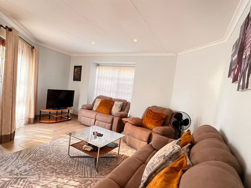 A comfortable living room featuring tiled flooring, recessed downlighting, and coved ceiling details, providing a functional and inviting space for relaxation.