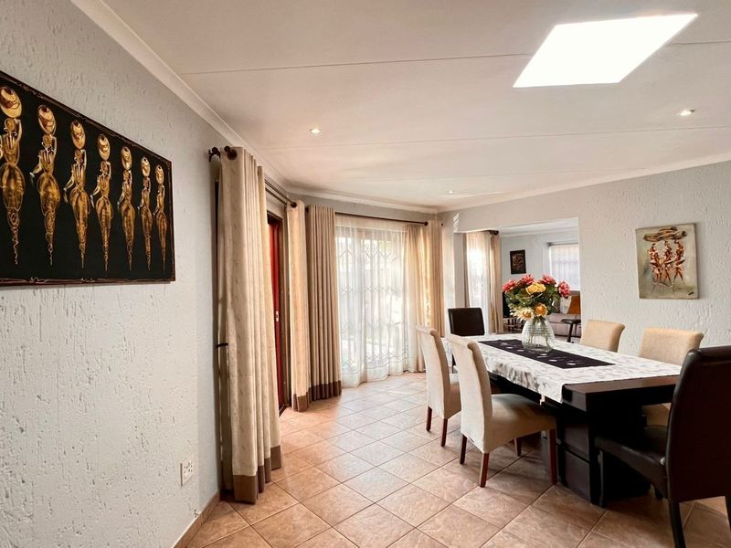 A bright dining room featuring tiled flooring, a skylight, and sliding glass doors that provide natural light and access to the outdoor area.