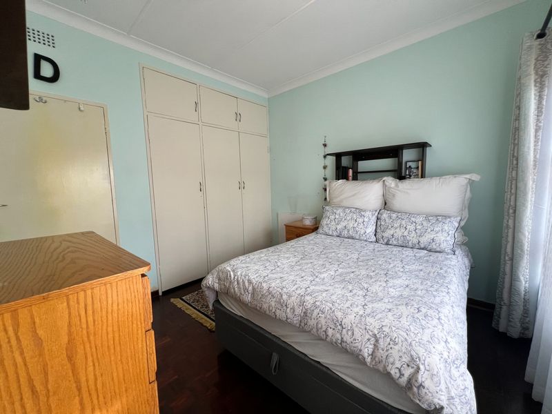 A bedroom featuring built-in cupboards, parquet flooring, and coved ceilings, offering a functional space with neutral wall tones.