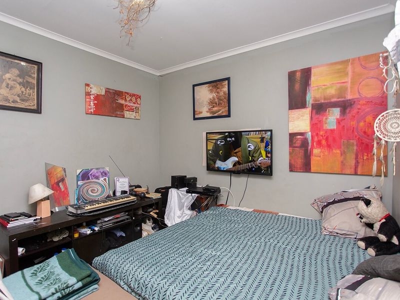 A standard bedroom featuring neutral wall paint, coving, and a ceiling rose, providing a functional space for rest.