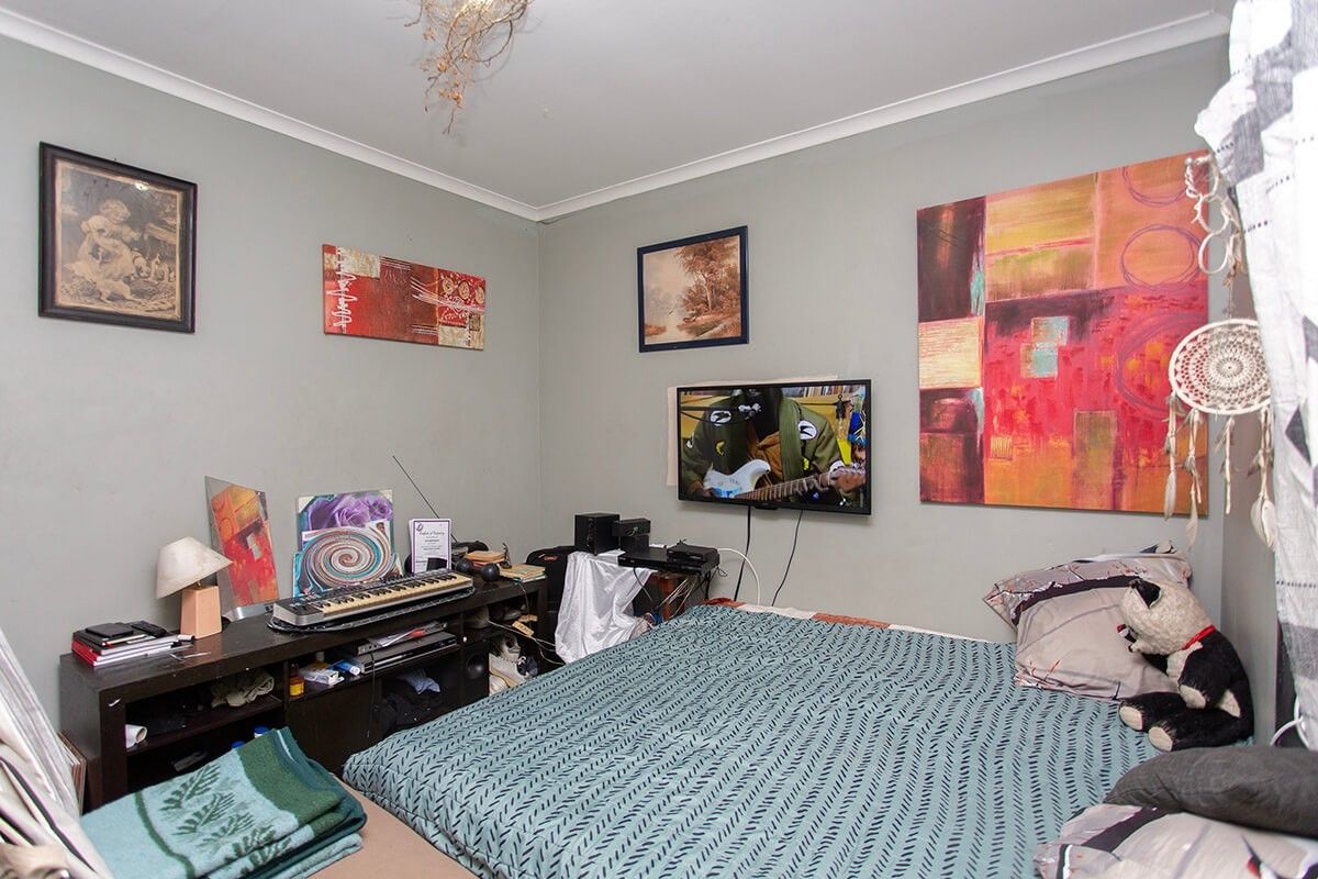 A standard bedroom featuring neutral wall paint, coving, and a ceiling rose, providing a functional space for rest.