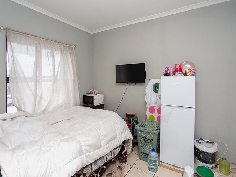 A bedroom featuring tiled flooring and coved ceilings, currently utilized as a multi-purpose living space.