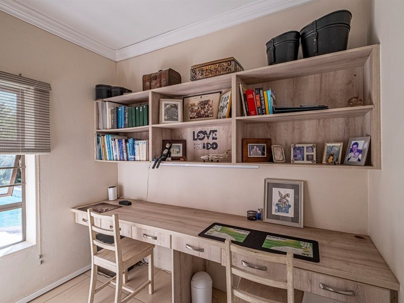 A functional home office featuring custom built-in timber-look desk and overhead shelving units, providing ample workspace and storage.