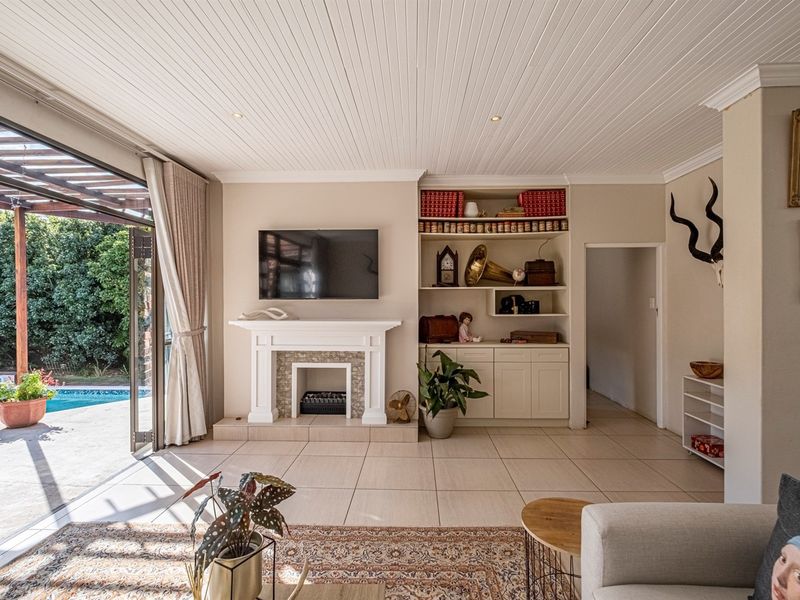 Spacious living room featuring a fireplace, built-in shelving, and large sliding glass doors that open directly onto the pool area.