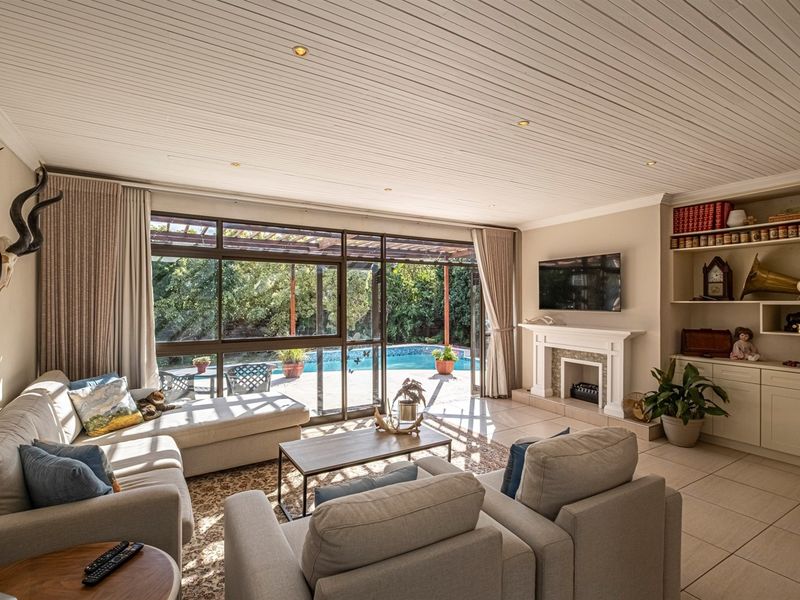 Spacious living room featuring a fireplace, built-in shelving, and large sliding glass doors that provide seamless access to the outdoor pool area.