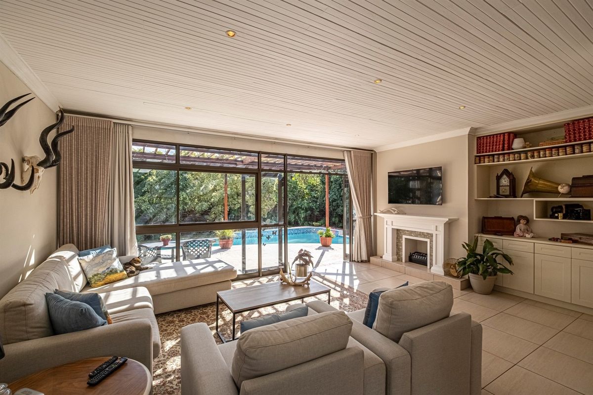 Spacious living room featuring a fireplace, built-in shelving, and large sliding glass doors that provide seamless access to the outdoor pool area.