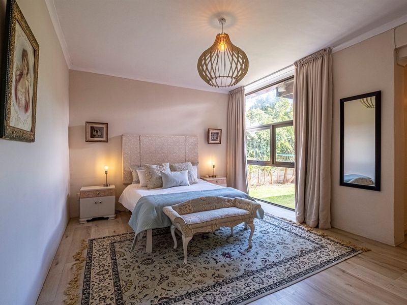A well-maintained bedroom featuring light laminate flooring, a large window providing natural light, and built-in cupboard storage.