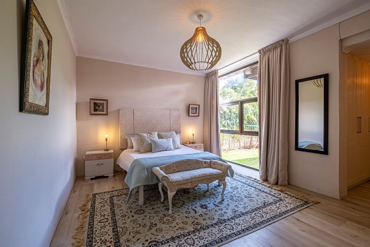 A well-maintained bedroom featuring light laminate flooring, a large window providing natural light, and built-in cupboard storage.