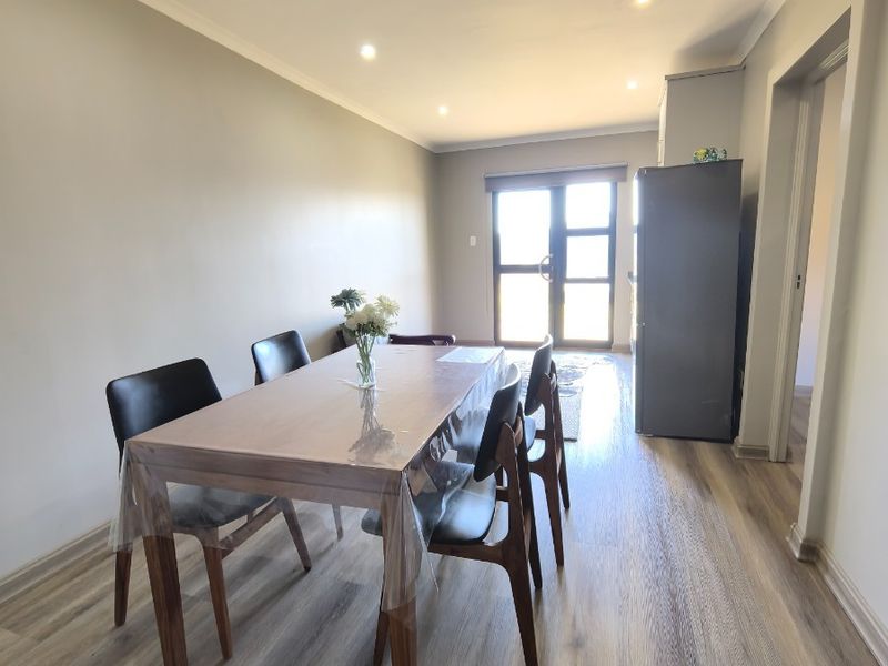 A bright dining area featuring modern laminate flooring, recessed downlighting, and a sliding glass door providing natural light and access to the exterior.